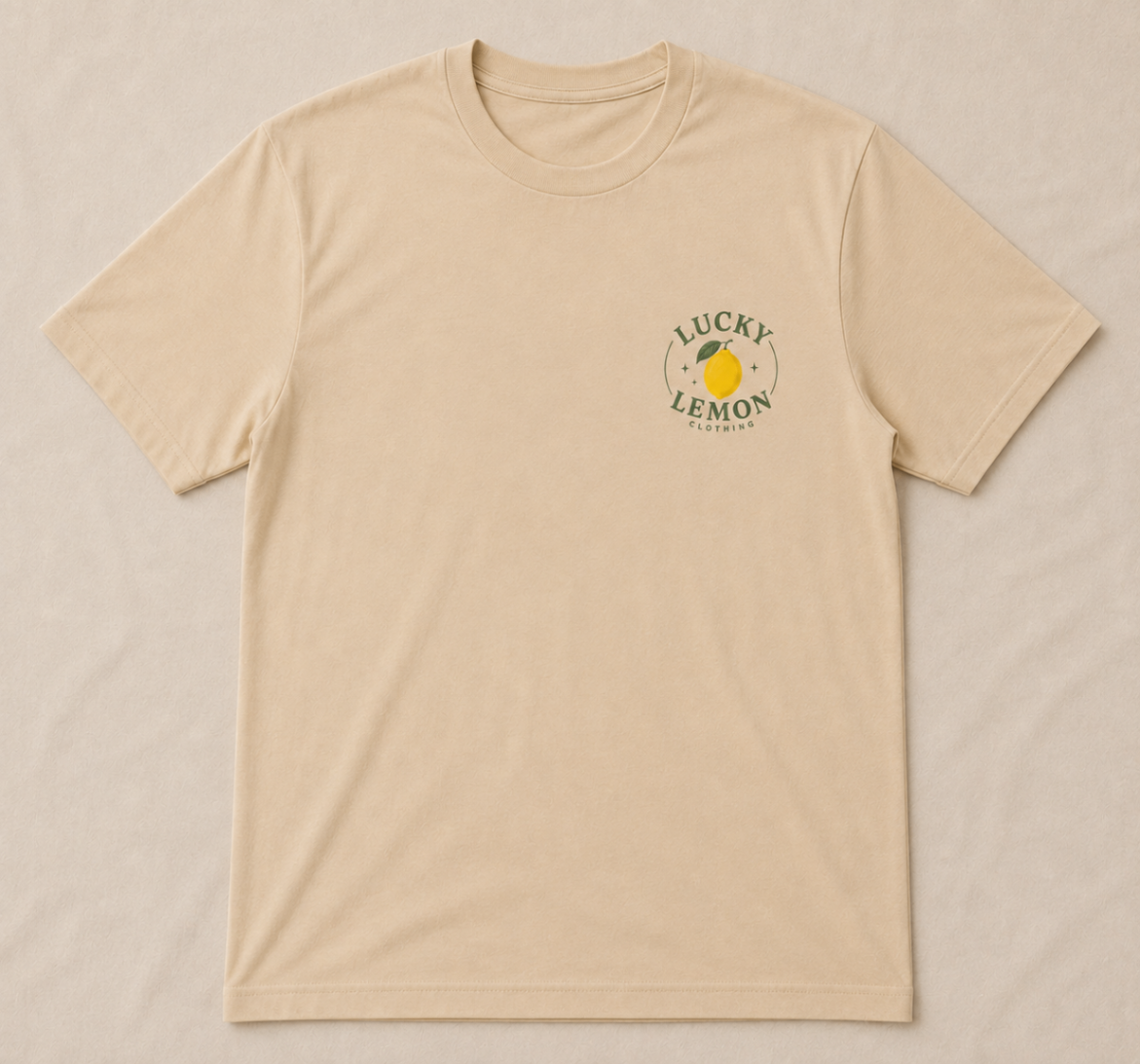 Lucky Lemon Everyday Tee in sand laid flat with the circular lemon badge printed on the right chest